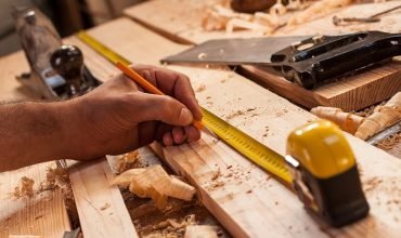 carpenter taking measurement of a wooden plank