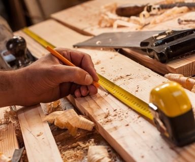 carpenter taking measurement of a wooden plank